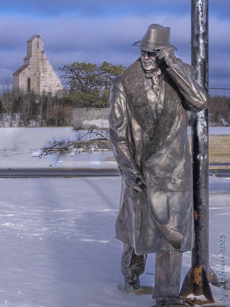 Mine shaft, frozen lake, statue of man in top hat and coat.