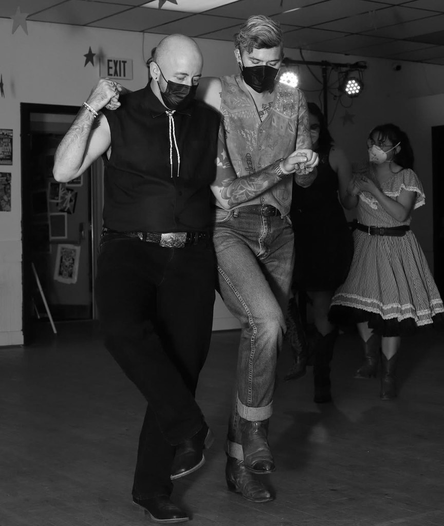 Masked people line dancing.
