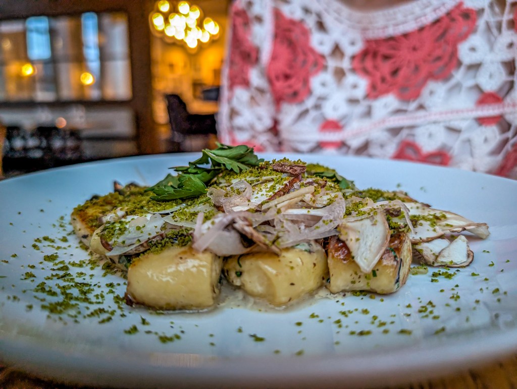 Fancy plated food, with mushrooms, herbs, possibyl gnocchi, onions...